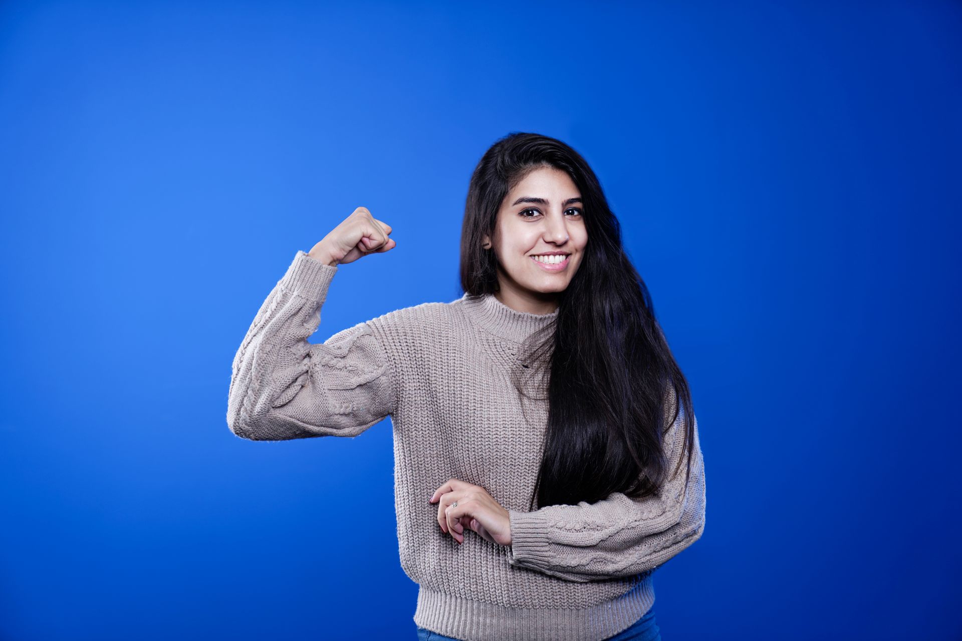 A woman in a sweater flexing