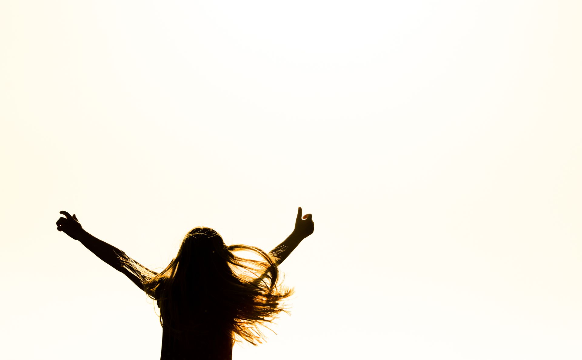 A silhouette of a woman reaching towards the sky